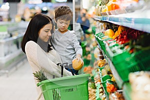 Mother and child shopping at farmer`s market for fruits and vegetables