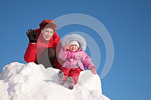 Mother with child sit on snow hill