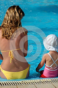 Mother and child sit in swimming pool