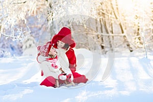 Mother and child sledding. Winter snow fun. Family on sleigh.