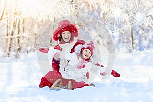 Mother and child sledding. Winter snow fun. Family on sleigh.