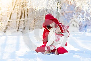 Mother and child sledding. Winter snow fun. Family on sleigh.