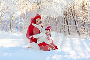 Mother and child sledding. Winter snow fun. Family on sleigh