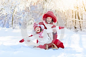 Mother and child sledding. Winter snow fun. Family on sleigh.