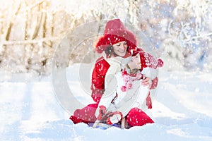 Mother and child sledding. Winter snow fun. Family on sleigh.