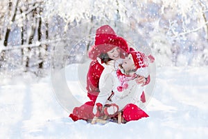 Mother and child sledding. Winter snow fun. Family on sleigh.