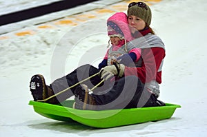 Mother with child on a snow slid slide downhill