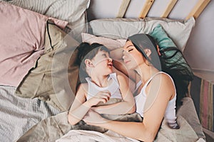 Mother and child son sleeping together in bed, waking up in the morning