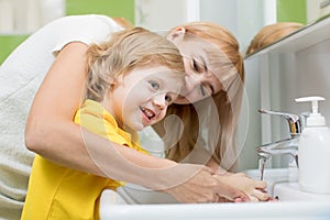 Mother and child son washing their hands in the bathroom. Care and concern for kids.
