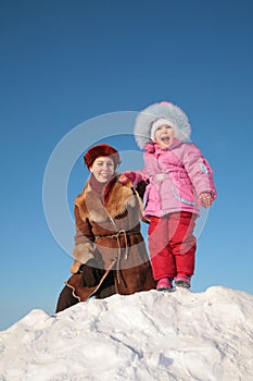 Mother with child stand on snow hill