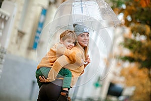 Mother and child on the street under an umbrella walking in rainy weather