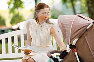 Mother with child in stroller reading book at park