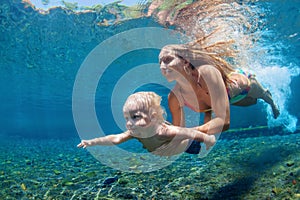 Mother with child swim and dive underwater in sea pool