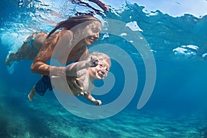 Mother with child swim underwater in blue beach pool