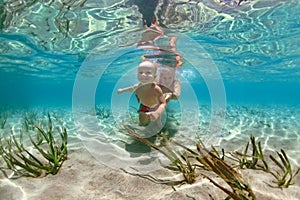 Mother with child swim underwater with fun in sea