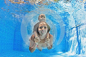 Mother with child swimming and diving underwater in pool