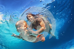 Mother with child swimming underwater in the pool