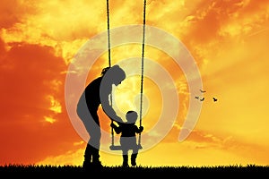 Mother and child on swing at sunset