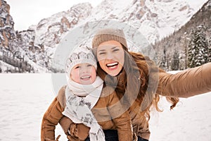 Mother and child taking selfie among snow-capped mountains