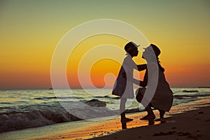 Mother and child tourists on ocean shore at sunset kissing