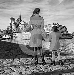 Mother and child travellers standing on embankment in Paris