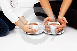 Mother with child warming hands with cup of tea.