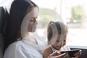 A mother and child watching tv on the train, traveling together