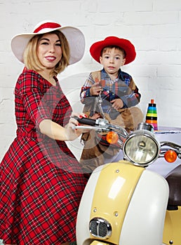 Mother and child wearing old fashioned clothes posing near scoot