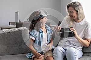 Mother and child wearing virtual reality headset vr glasses in living room at home having fun