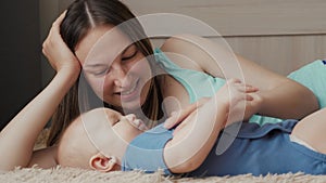 Mother and child on a white bed. Mom and baby boy in diaper playing in sunny bedroom. Parent and little kid relaxing at