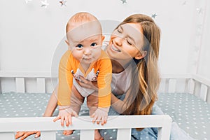 Mother and child on a white bed. Mom and baby boy are playing. A parent and a small child are resting at home. Family has fun