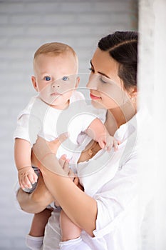 Mother and child in a white room. Mom and baby boy in diaper pla