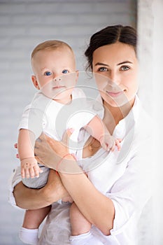 Mother and child in a white room. Mom and baby boy in diaper pla