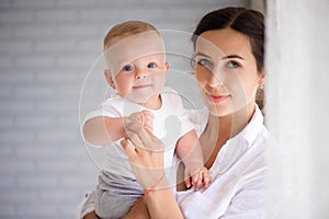 Mother and child in a white room. Mom and baby boy in diaper pla