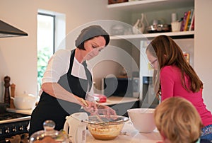 Mother, children and baking in kitchen in home, family and bonding together with mixing machine on counter table. Mom