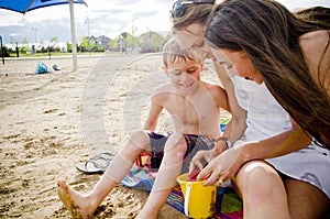 Mother and children on beach with sand bucket