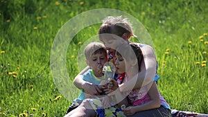 The mother with children blowing on a dandelion