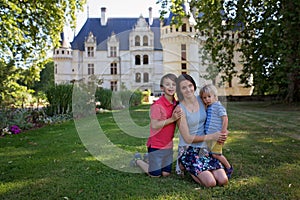 Mother and children in castle garden, smiling at camera, castle on Loire Valley