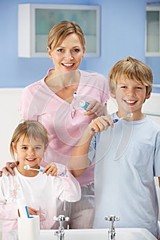 Mother and children cleaning teeth in bathroom