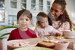 Mother And Children Decorating Cookies At Home Together