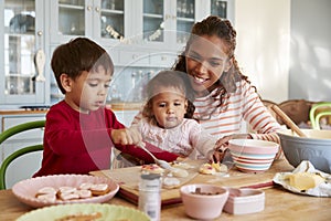 Mother And Children Decorating Cookies At Home Together