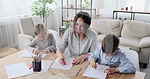 Mother with children drawing on paper at home