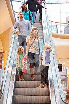 Mother And Children On Escalator In Shopping Mall