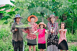Mother and children family holding seeding plants to planting tree on blurred green nature background