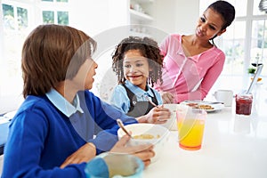 Mother And Children Having Breakfast Before School