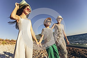 Mother and children holding hands enjoying the sunset on the beach.