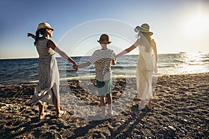 Mother and children holding hands enjoying the sunset on the beach.