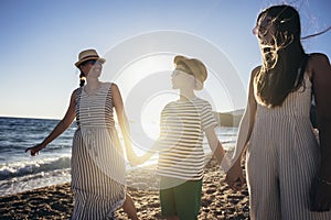 Mother and children holding hands enjoying the sunset on the beach.