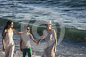 Mother and children holding hands having fun on the beach.