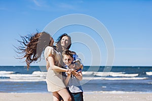 Mother and children hugging on the beach